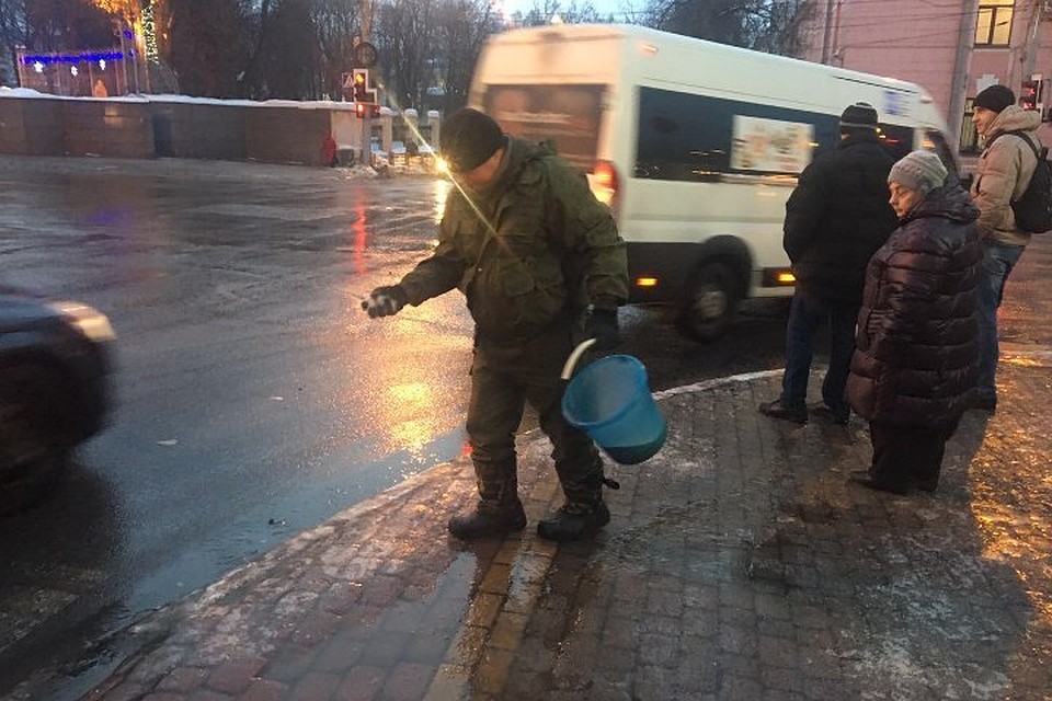 Рабочие посыпают остановки и тротуары вручную.