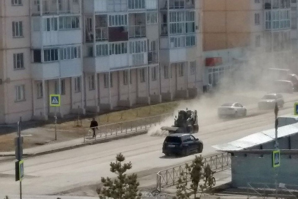 Дорожная техника подняла пыль, окутав всю дорогу и проезжающие мимо машины.