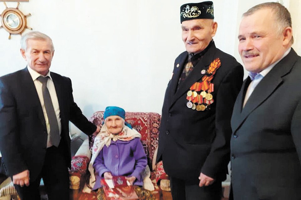 Глава Пировского района Александр Евсеев и глава Солоухинского поселения Рафаил Гинатуллов вручают юбилейные награды ветерану Великой Отечественной войны Исламу Зарипову и его супруге — труженице тыла.
