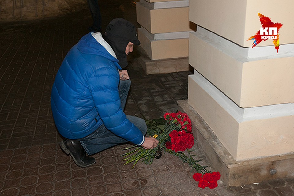 Люди молча оставляют гвоздики и розы у дверей заксобрания, где работал политик