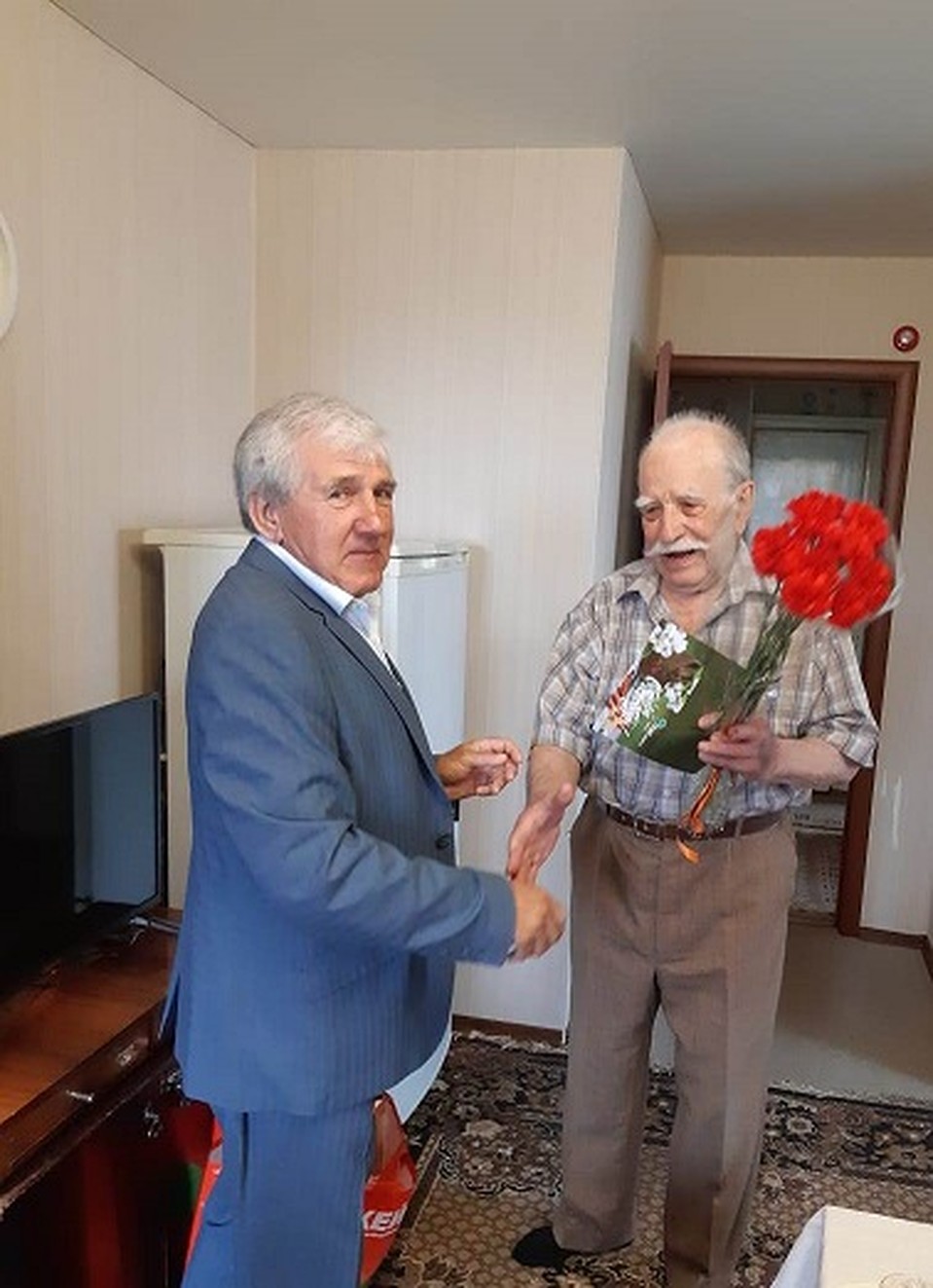 Петр Терентьевич Бородинов принимает поздравления от председателя профкома "ТНС энерго" В.М. Костенко