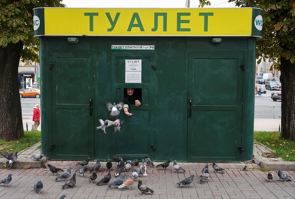 Работница платного туалета в центре Киева кормит голубей. Фото: REUTERS
