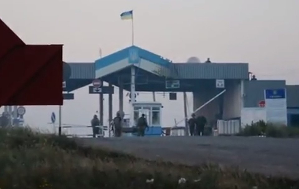 Украинские пограничники уносят раненных с пункта пропуска