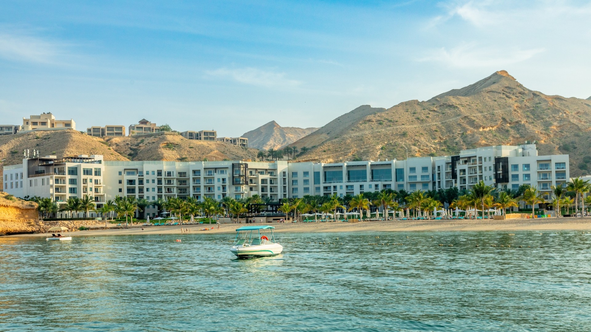 Отель Jumeirah Muscat Bay с видом на море и горы.